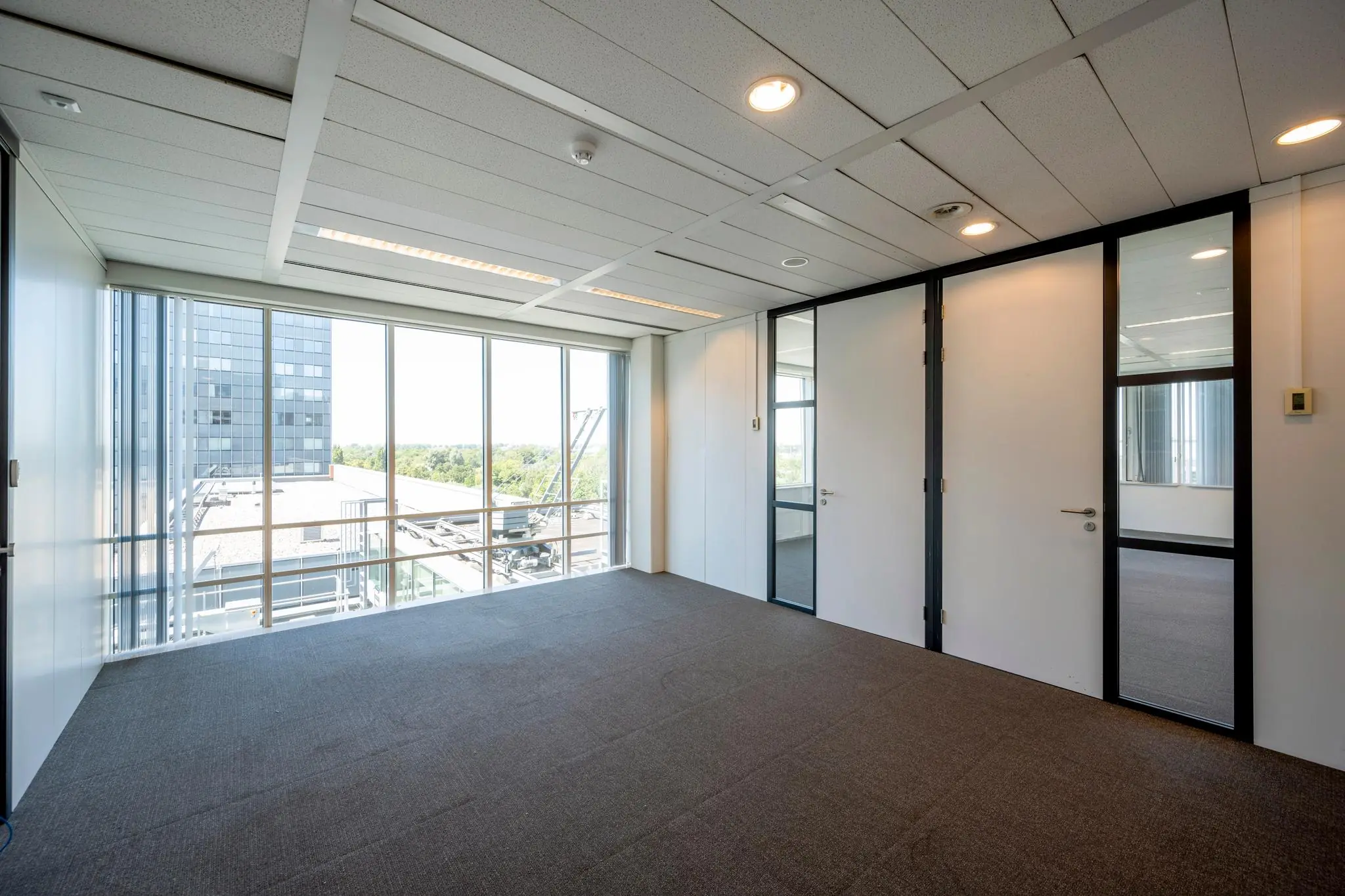 Licht en modern kantoorruimte aan de Thomas R. Malthusstraat met grote ramen en uitzicht op een naastgelegen kantoorgebouw.